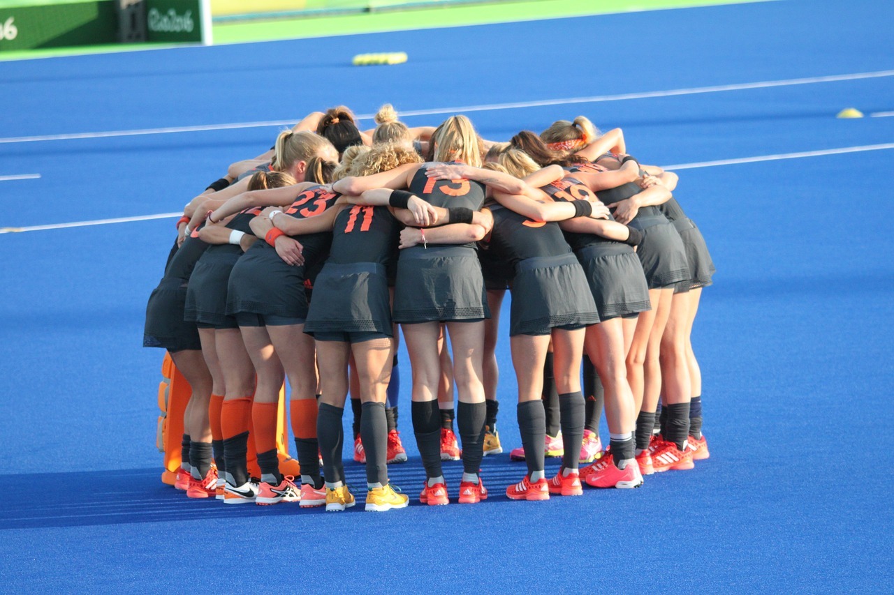 Hockey Outfield Players in a Huddle Avoiding The Hockey Goalkeeper Warm Up